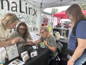 Women getting permanent jewelry at a Missouri vendor market event